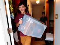 Luis Gonsalves, looks on, as his brother Victor Gonsalves is all smiles as he brings a bin of items he needs to the car, as he prepares to leave from his home on Harvard Street in New Bedford  for his first year at Harvard University.  PHOTO PETER PEREIRA