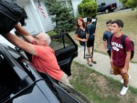 Raul Bourguignon, stepfather, loads the duffle bag onto the top of the SUV as Raquel Bourguignon, holds a mirror that Victor Gonsalves is bringing, as he prepares to leave from his home on Harvard Street in New Bedford  for his first year at Harvard University.  PHOTO PETER PEREIRA