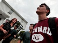 Victor Gonsalves looks on as his stepfather loads up his bags.  In the background, Raquel Bourguignon holds a mirror Victor is brining with him to school, reflecting his brother Luis Goncalves, as he prepares to leave from his home on Harvard Street in New Bedford  for his first year at Harvard University.  PHOTO PETER PEREIRA