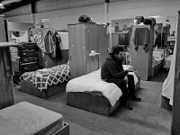 A resident browses the web on his phone atop one of the forty beds at the House of Hope homeless shelter on Mount Pleasant Street in New Bedford.