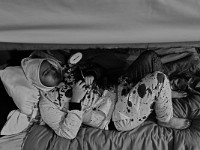 Justin Quintin plays a game on his phone while lying down on his bed at the House of Hope homeless shelter on Mount Pleasant Street in New Bedford.