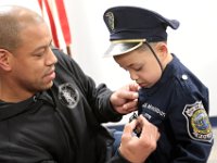 Officer Shane Harris pins a badge on JJ Montalban's, 6, uniform after he was sworn in as an honorary New Bedford police officer at a ceremony held at police headquarters on Rockdale Avenue in New Bedford.  JJ Montalban, who was born with various congenial heart defects, is currently in need of a heart transplant. PHOTO PETER PEREIRA