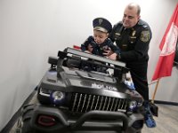 Officer Scott Carola helps JJ Montalban, 6, onto his new 'cruiser' after JJ was sworn in as an honorary New Bedford police officer at a ceremony held at police headquarters on Rockdale Avenue in New Bedford.   JJ Montalban, who was born with various congenial heart defects, is currently in need of a heart transplant. PHOTO PETER PEREIRA