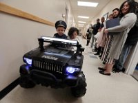 Angelie Montablan, right, looks on as her son JJ Montalban, 6, who was born with various congenial heart defects, gives his sister Mikaelah Montablan a ride aboard his new cruiser after he was sworn in as an honorary New Bedford police officer at a ceremony held at police headquarters on Rockdale Avenue in New Bedford.   JJ Montalban, who was born with various congenial heart defects, is currently in need of a heart transplant. PHOTO PETER PEREIRA