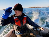 Matt Loo shields his face from the rising son as he head back to port after collecting his morning oysters from his farm at Jack's Cove off of West Island in Fairhaven, MA.