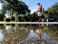 Brad Hathaway, 88, is reflected on a puddle on North Road in Mattapoisett, as he goes for his daily walk nearing his goal of 24,901 miles of walking since he began in 1988.  Mr. Hathaway who was recently diagnosed with Parkinson's, is attempting to walk the Earth's circumference while trying to raise money for the Mattapoisett Land Trust in an effort to preserve the land surrounding Aucoot Cove in Mattapoisett.  PHOTO PETER PEREIRA