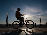 A man takes a ride on his bicycle around the south end of New Bedford as the sun rises in the distance.  PHOTO PETER PEREIRA