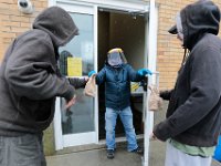 In light of the coronavirus pandemic, volunteer, Trung Dong uses a face mask and a shield, as he hands out meals to two homeless men at the Sister Rose House food pantry in the south end of New Bedford. The homeless are no longer allowed in the building and collect lunch at the door.  PHOTO PETER PEREIRA