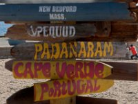 From this perspective, a man doing stretches against the pier wall, looks like he thinks the Padanaram sign needs to be pointed in a new direction, on a set of signs pointing to different parts of the city and the world installed on East Beach in New Bedford. PHOTO PETER PEREIRA
