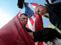 New Bedford firefighters Miguel Cabral and Capt. Kurt Houghton hoist a giant American flag in preparation to celebrate Fr Mike Racine's 25th anniversary of his ordination, held in the parking lot of the Saint Lawrence church in New Bedford.  PHOTO PETER PEREIRA