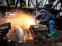 Ray Winston of Blue Fleet Welding,sends sparks flying while using a cutting torch to make modifications to the dredges aboard the scalloper docked in New Bedford. PHOTO PETER PEREIRA
