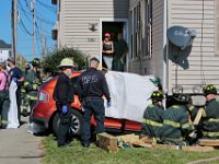 Residents of the three family home on Hemlock Street in New Bedford are stunned by the scene in front of their door, as New Bedford  police and fire crews respond to an SUV which crashed into the side of the structure in the south end of New Bedford.   PHOTO PETER PEREIRA