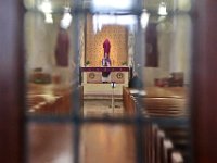 Father Mike Racine is seen through the glass on entrance door, as he conducts mass to an empty church at the Holy Name of the Sacred Heart of Jesus Church on Mount Pleasant Street in New Bedford.  The mass was recorded then uploaded to YouTube and Facebook for parishioners to watch.  PHOTO PETER PEREIRA]