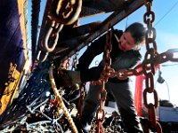Crystal Vaughn cuts away the twine top from the dredge, as she makes repairs before heading back out to sea. Crystal Vaughn is the mate of the fishing boat Reliance a scalloper out of the port of New Bedford.