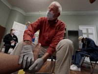 Doctor Douglas Fogg takes a closer look at the feet of a homeless man during the weekly Mercy Meals podiatry clinic for the homeless on Purchase Street in New Bedford.