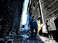 New Bedford firefighter, Rick Vigeant walks the alley separating the charred remains of two mixed-use residential and commercial buildindings on Acushnet Avenue, where two people died in the early Morning blaze in New Bedford.