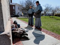 Franciscan Friars, Father Matthias and Father Andre, stop to speak with a homeless man sleeping on the side of a buiding at Custom House Square, during their weekly walk to connect with those in need in the community.