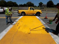 A yellow pickup truck drives past, as Kurt Charbonneau and Mark Verdejo re-paint the yellow crosswalk on the south heading side of West Rodney French Boulevard in New Bedford.