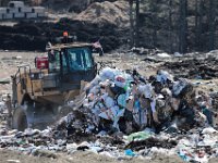 A trash compactor uses it's special wheels to flatten the newly arrived trash, as it moves it into place at the Crapo Hill Landfill in New Bedford.