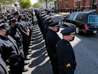 The hearse of New Bedford police officer Sgt. Michael Cassidy passes officers standing at attention on the way to the funeral mass held at Our Lady of Mount Carmel Church.