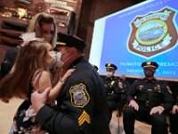 New Bedford Police officer Kevin Lawless, gives his daughter Morgan Lawless, 4, a kiss after she and her mother, Kara Lawless pinned the sergeant badge on his uniform during a promotion ceremony held in the Whaling Museum auditorium.