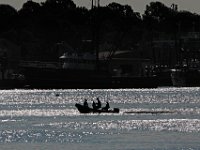 Boaters make their way across New Bedford harbor as the rising sun glistens on the water.