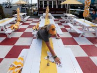 Marcie Araujo, center, and Abby Lopes, right, clean the Clam Bar tables set on a colorful ground, before opening time on New Bedford's waterfront.