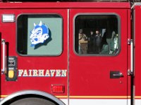 Fairhaven Fire Department Chief, Timothy Francis, waves to those in attendance in front of Fairhaven Town Hall, after receiving a plaque from Chairman of the Board of Selectmen, Daniel Freitas, celebrating 42 years of service, as seen through the window of Ladder One which he took for a final ride around town.