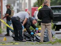 A State Police officer collects evidence from under the tarp topped with sandbags containing a potentially explosive device found in front of 65 Mosher Street in New Bedford.