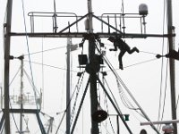 A painter walks the high wire, as he paints the mast of a fishing boat in New Bedford.
