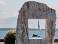 Youngsters sailing are seen through a granite sculpture insalled at a pier in the south end of New Bedford.