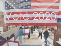 An American flag hangs from the ceiling, as voters cast their votes for the 2020 Presidential election inside of the Normandin Middle School polling station in New Bedford.  [ PETER PEREIRA/THE STANDARD-TIMES/SCMG ]