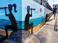 A passenger heading to Nantucked aboard the high speed ferry makes his way up the ramp to the State Pier terminal in New Bedford past a mural painted on the side wall.  PETER PEREIRA/THE STANDARD-TIMES/SCMG