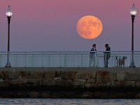 People watch the super moon rise from the pier at Fort Taber Park in the south end of New Bedford.   PETER PEREIRA/THE STANDARD-TIMES/SCMG