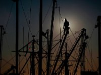 The sun rises behind a workman using a grinder to remove the paint from an outrigger of a fishing boat being re-painted in New Bedford harbor.   PETER PEREIRA/THE STANDARD-TIMES/SCMG