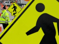 A New Bedford police officer monitors traffic between the men working signs, as workmen repair the street and sidewalks on Fish Island in New Bedford.   PETER PEREIRA/THE STANDARD-TIMES/SCMG