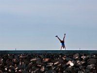 A woman performs some cartwheels after doing some early morning yoga atop the hurricane barrier in the south end of New Bedford.   PETER PEREIRA/THE STANDARD-TIMES/SCMG