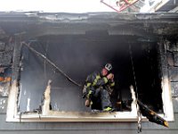 New Bedford firefighter Lt. Kevin Farnworth grabs some fresh air to try and adjust his breathing apparatus while fighting a fire at a single family home on Tremont Street in New Bedford.  [ PETER PEREIRA/THE STANDARD-TIMES ]