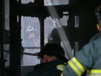 New Bedford firefighters can be seen battling the fire on Tremont Street in New Bedford from both sides of the single family home. [ PETER PEREIRA/THE STANDARD-TIMES ]