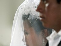 Isidro Himon, 18, and Carmelina Hernandez, 18 are wed at the Peroquia de Santo Christo church in Zacualpa, Guatemala.  Maria Gutierez, godmother of the couple fixes the veil atop Carmelina's head in preparation for the wedding.
