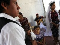 Isidro Himon, 18, and Carmelina Hernandez, 18 are wed at the Peroquia de Santo Christo church in Zacualpa, Guatemala.  Maria Gutierez, godmother of the couple fixes the veil atop Carmelina's head in preparation for the wedding.