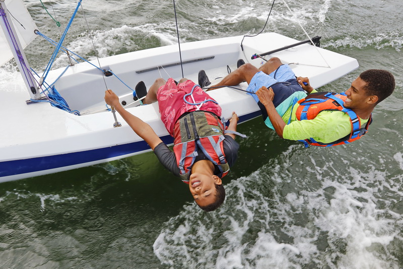 Alex Parreira and junior instructor Adilson DeBrito, are enjoying pure bliss as they lean over to keep their sailboat from flipping, while sailing. Students involved in the Community Boating Center's Summer Youth Sailing Program, enjoy a day of sailing in Clarkes Cove in New Bedofrd  for the last time, as the 8 week program comes to an end tomorrow.  PHOTO PETER PEREIRA