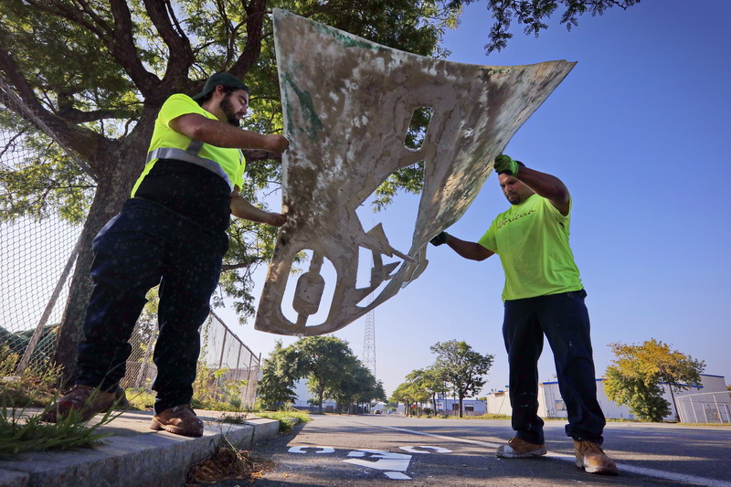 New Bedford DPI's Danni Ortiz and Roger Pimental lift the cyclist template after painting the bike path signage on McArthur Drive as part of re-painting them throughout the city. PHOTO PETER PEREIRA