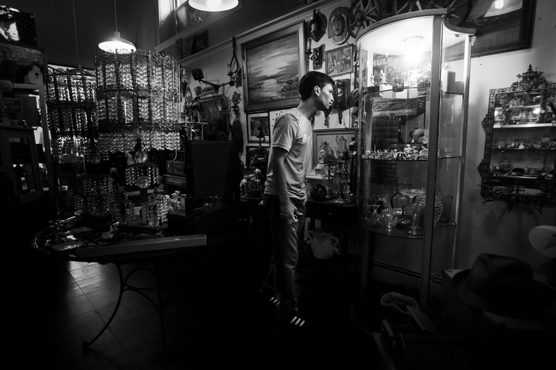 Avi Santiago discovers an item he is interested in, inside a lit display case at Cottage Antiques on Union Street in downtown New Bedford, MA. PHOTO PETER PEREIRA