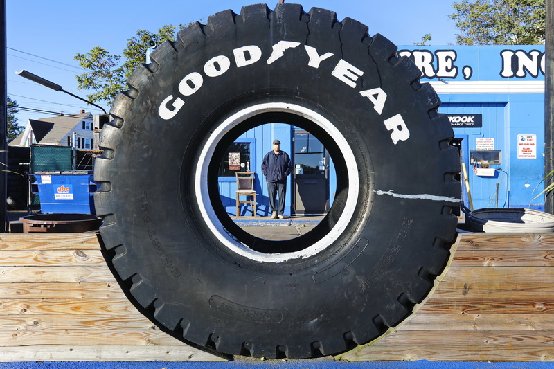 Ralph Desjardins waits for his tire to be replaced as seen throught the giant tire in front of Joe's Tire on Acushnet Avenue in the north end of New Bedford.