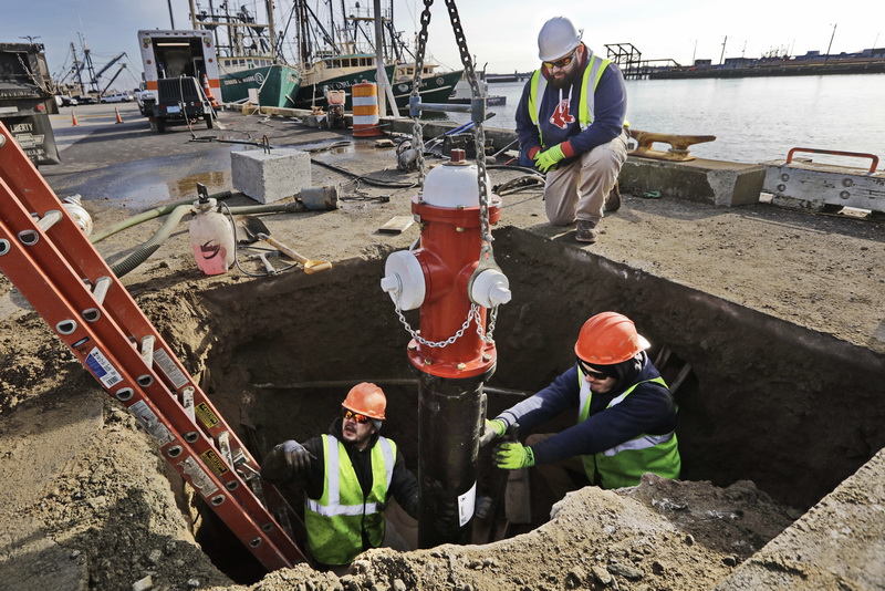 New Bedford DPI Foreman, Manny Washburn above, looks on as pipe fitters Kevin Sylvia and Jordan Arruda, manuever a new fire hydrant replacement into place on the waterfront.   PHOTO PETER PEREIRA