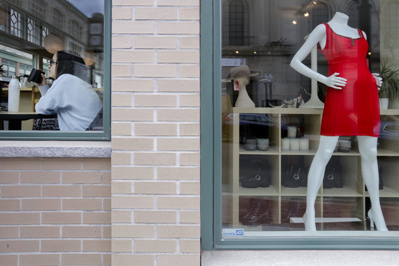 A woman enjoys a cup of coffee at the Green Bean, as a  mannequin displays a red dress for sale next door at Calico on Union Street in downtown New Bedford, MA.   PHOTO PETER PEREIRA