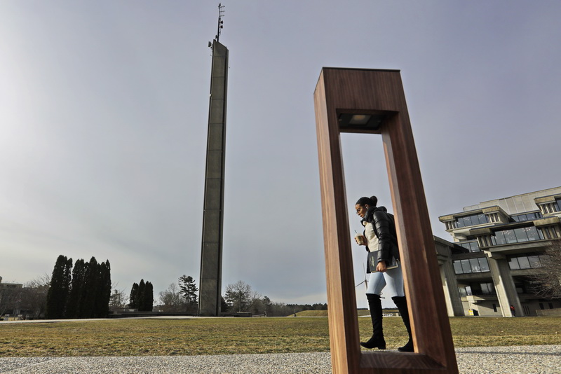 A student walks past one of the new rectangular wooden light fixtures lining the walkways in the central part of the UMass Dartmouth campus in Dartmouth, MA.   PHOTO PETER PEREIRA