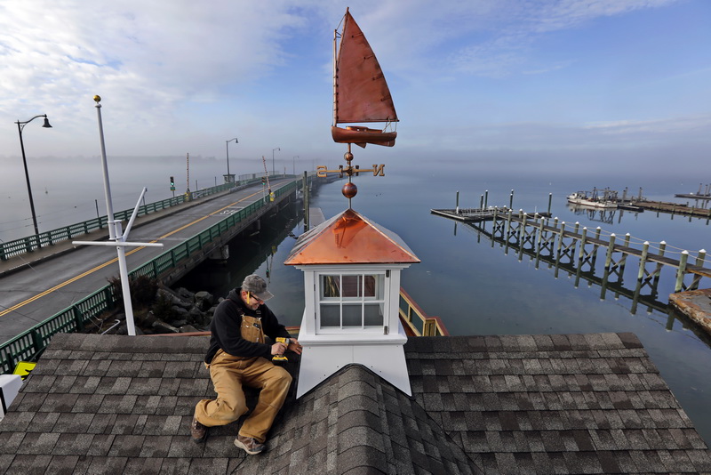 Foreman, Donald Jusseaume of R. P. Valois & Company installs the cupola and copper sailboat weathervane, atop the new Maritime Center in Padanaram on a foggy morning in South Dartmouth, MA.    PHOTO PETER PEREIRA