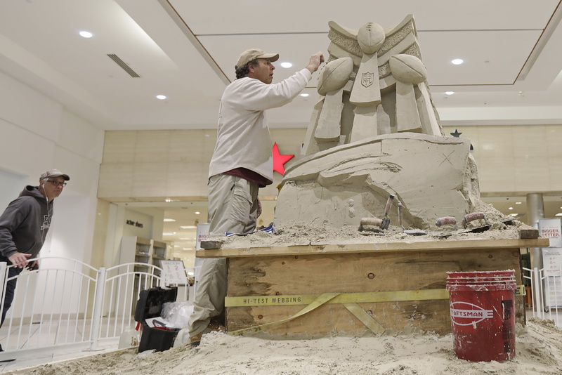 A shopper takes a closer look. as Steve Topazio of Sandtasia, carves a sand sculpture celebrating the New England Patriots Super Bowl victory, in the central section of the Dartmouth Mall.  PHOTO PETER PEREIRA